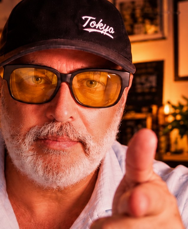 Rafa Casas, copywriter, con gorra y gafas amarillas, señalando a cámara